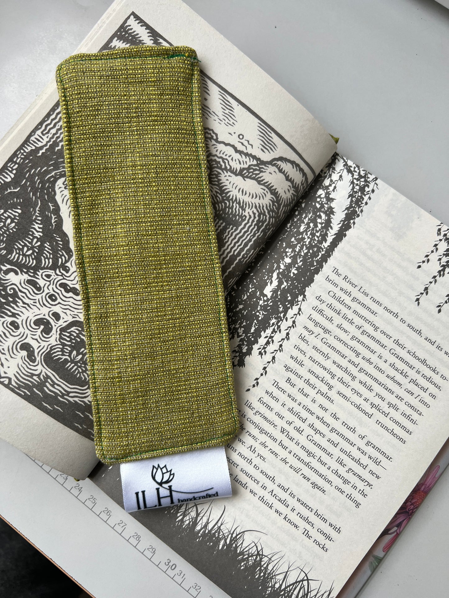 Green fabric pouch on an open book with a visible brand tag.